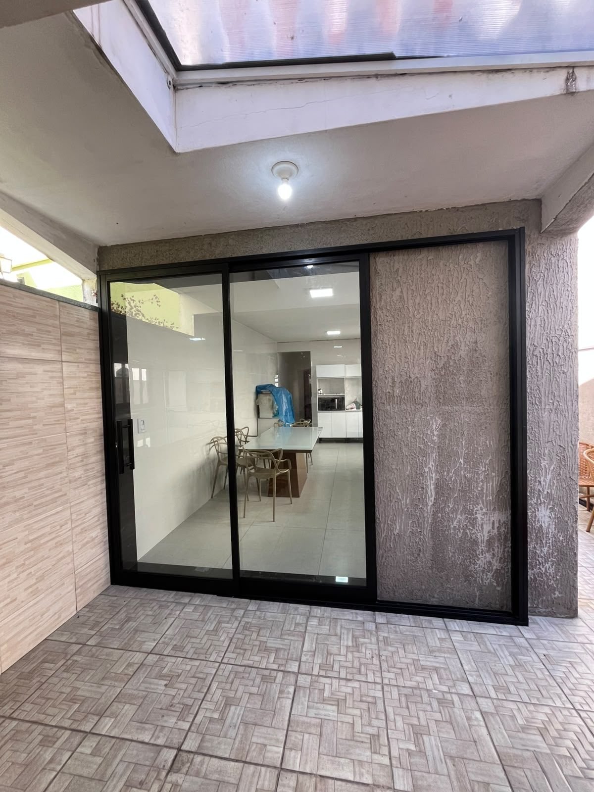 Porta de correr em alumínio preto com vidro, instalada entre a área externa e a cozinha